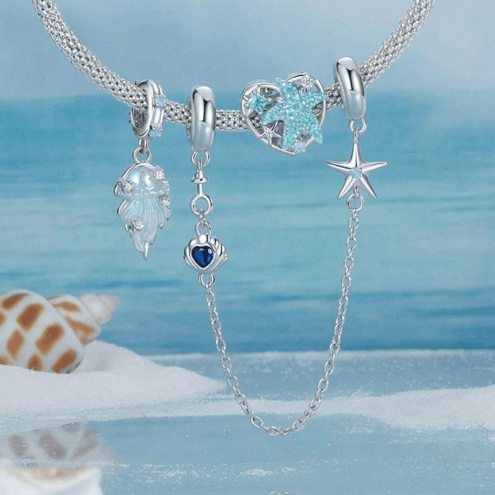 Sterling silver jellyfish dangle charm with iridescent enamel body, flowing tentacle design, and small clear gemstones on the bail and charm