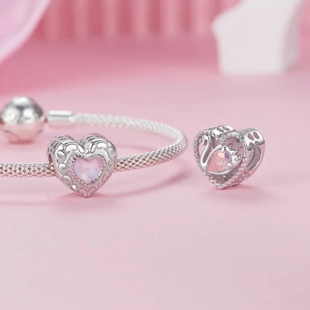 Silver bracelet with heart-shaped charm on a pink background