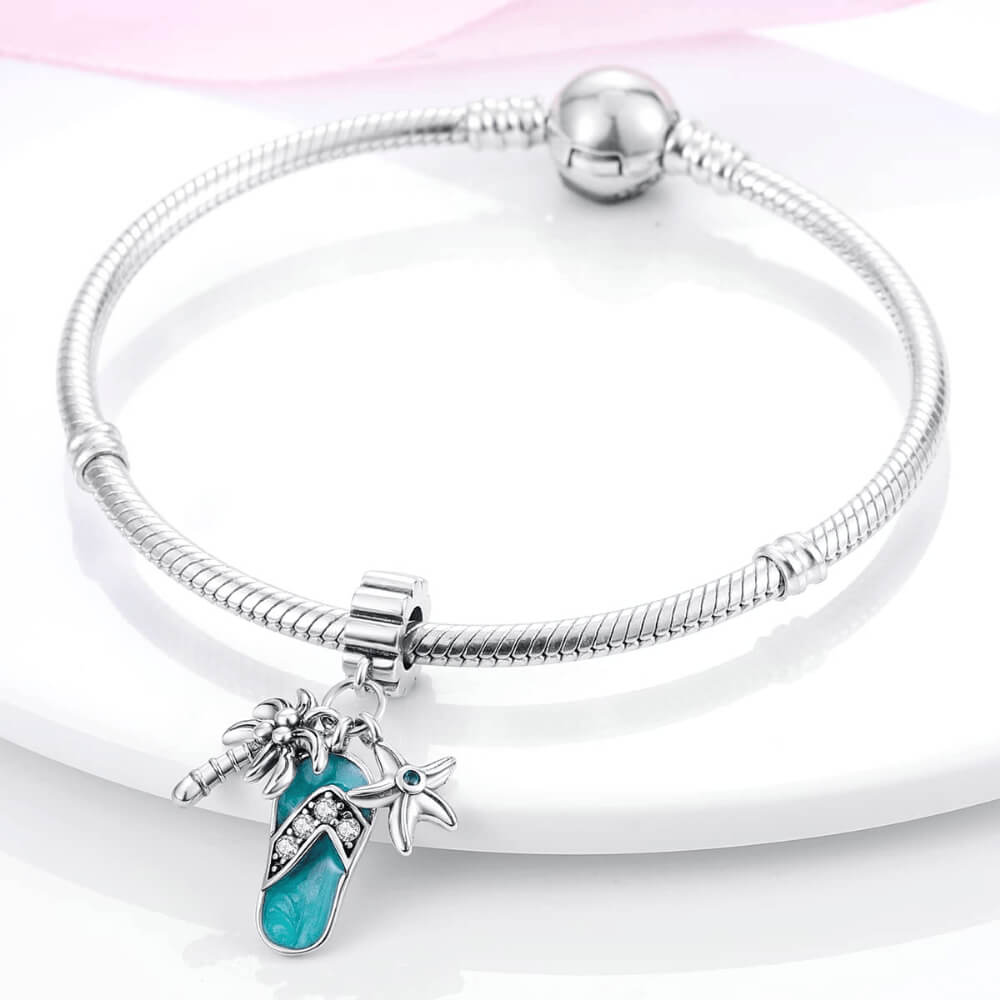 Sterling silver flip-flop charm with teal enamel, palm tree, starfish, and gemstones.