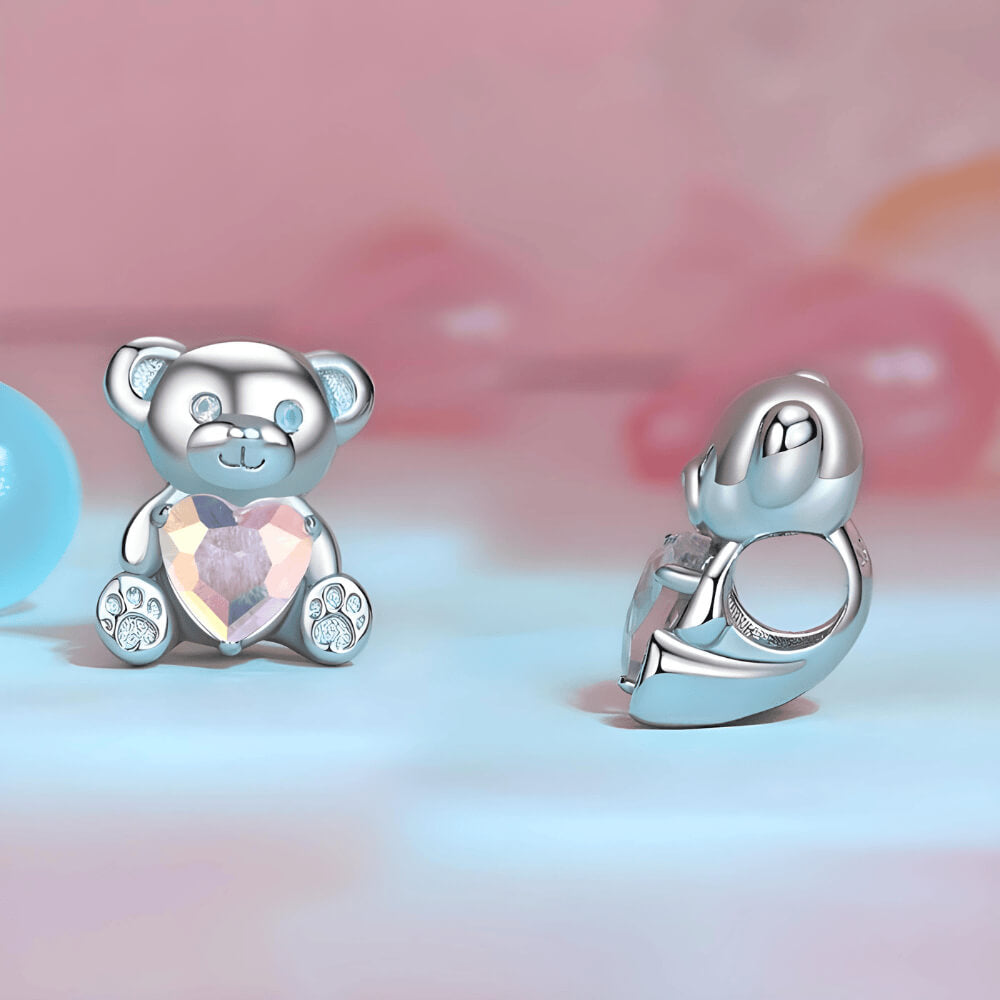 Sterling silver teddy bear charm holding an iridescent heart-shaped crystal with paw-print feet 