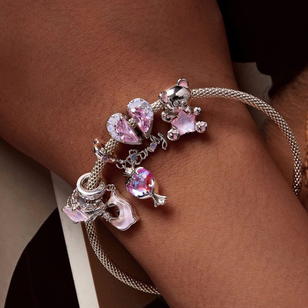 Sterling silver teddy bear charm holding pink star crystal with enamel details.