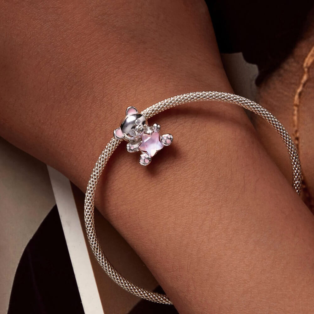 Sterling silver teddy bear charm holding pink star crystal with enamel details.