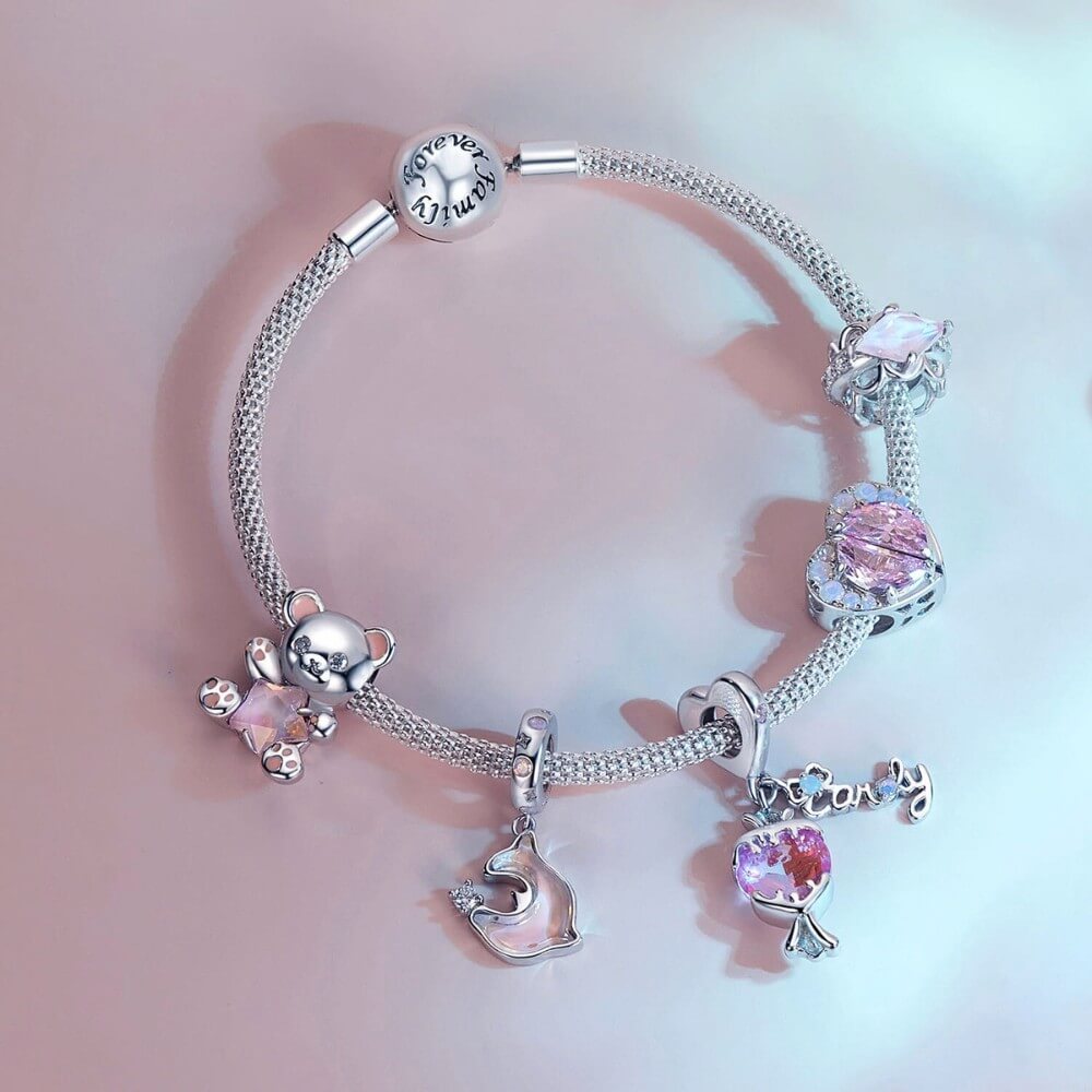 Sterling silver teddy bear charm holding pink star crystal with enamel details.