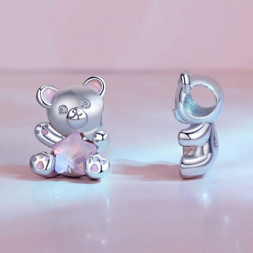 Sterling silver teddy bear charm holding pink star crystal with enamel details.