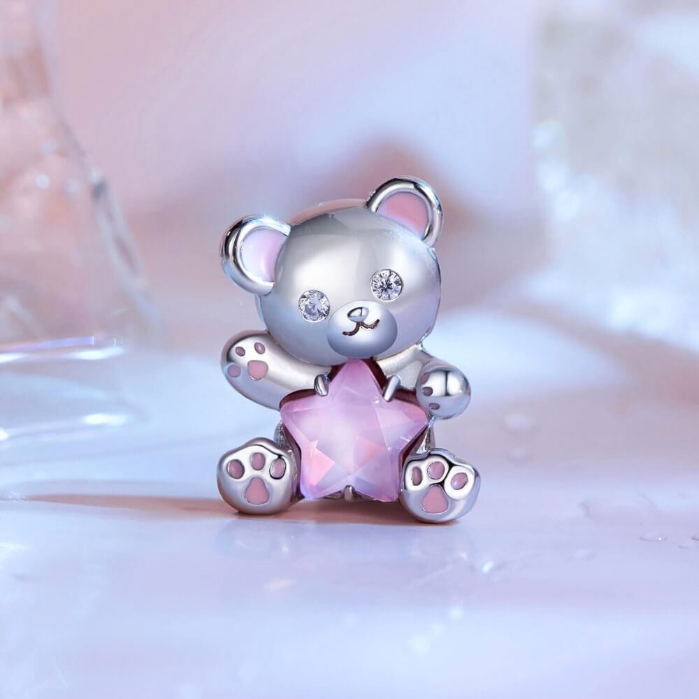 Sterling silver teddy bear charm holding pink star crystal with enamel details.