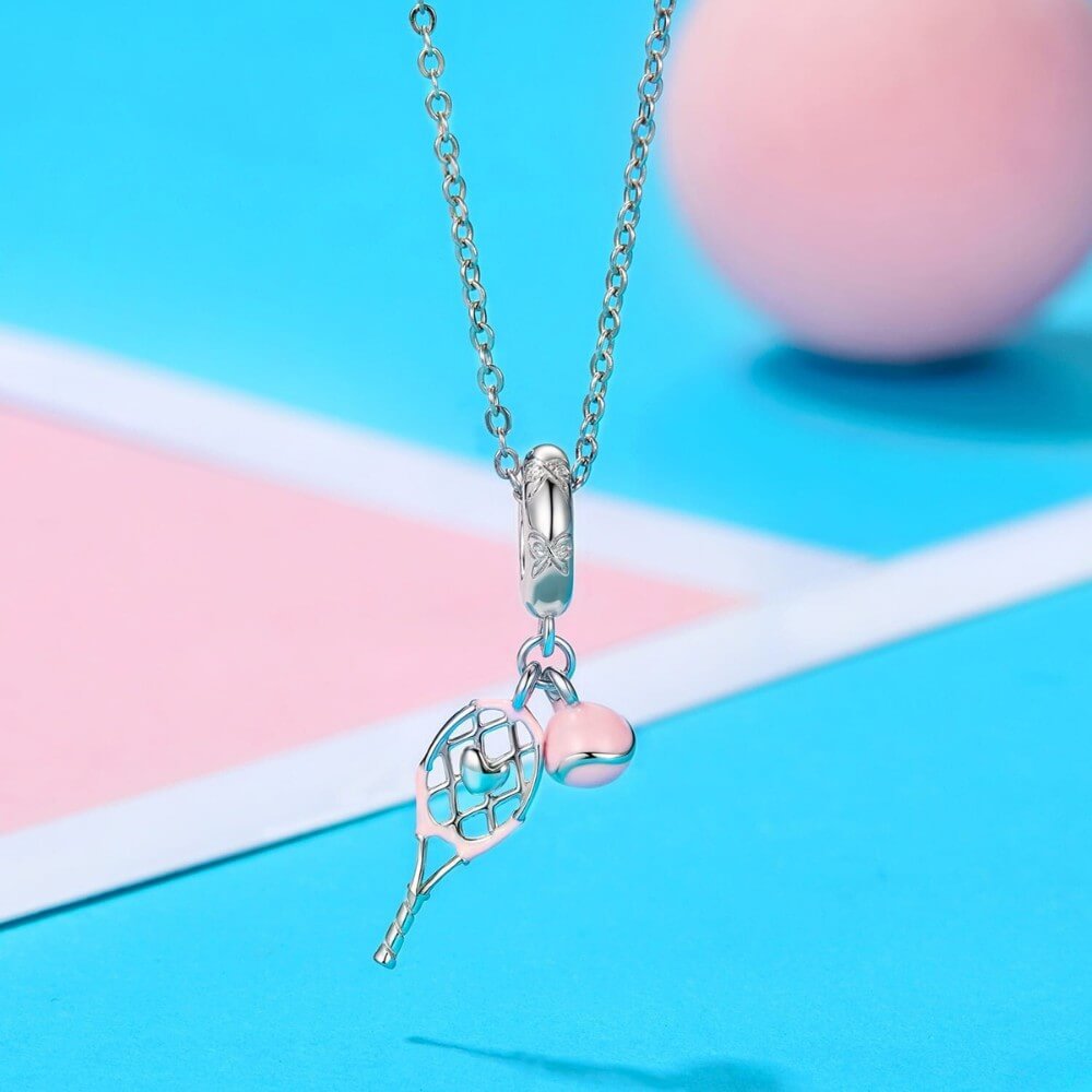 Sterling silver tennis racket charm with pink enamel ball.