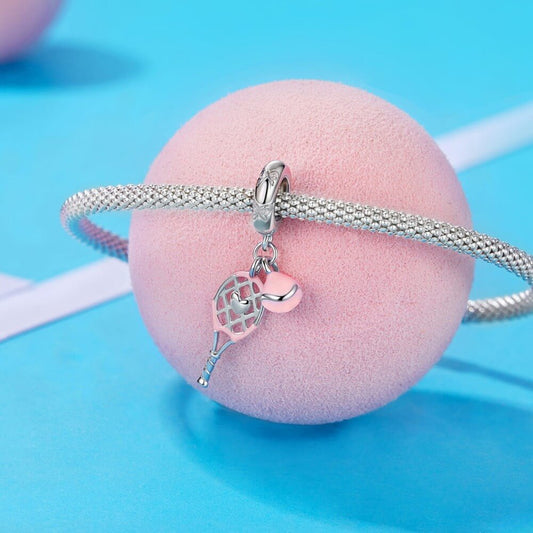 Sterling silver tennis racket charm with pink enamel ball.