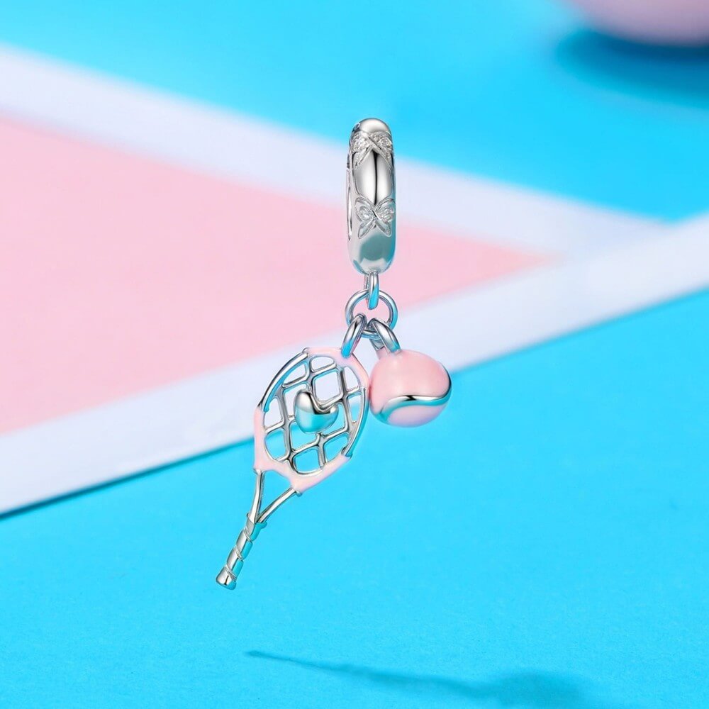 Sterling silver tennis racket charm with pink enamel ball.