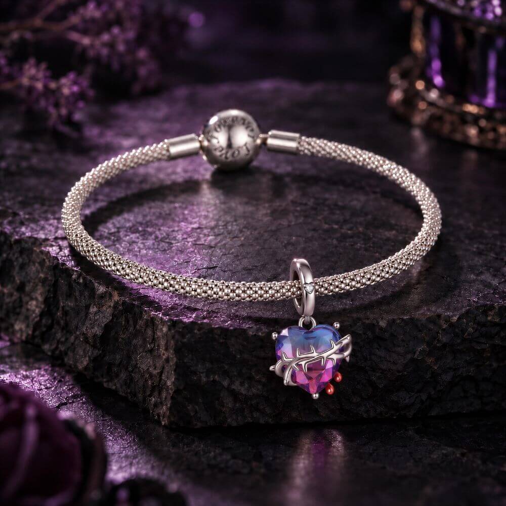 Sterling silver heart charm with blue pink crystal, thorned vine detail, and red drop accents.