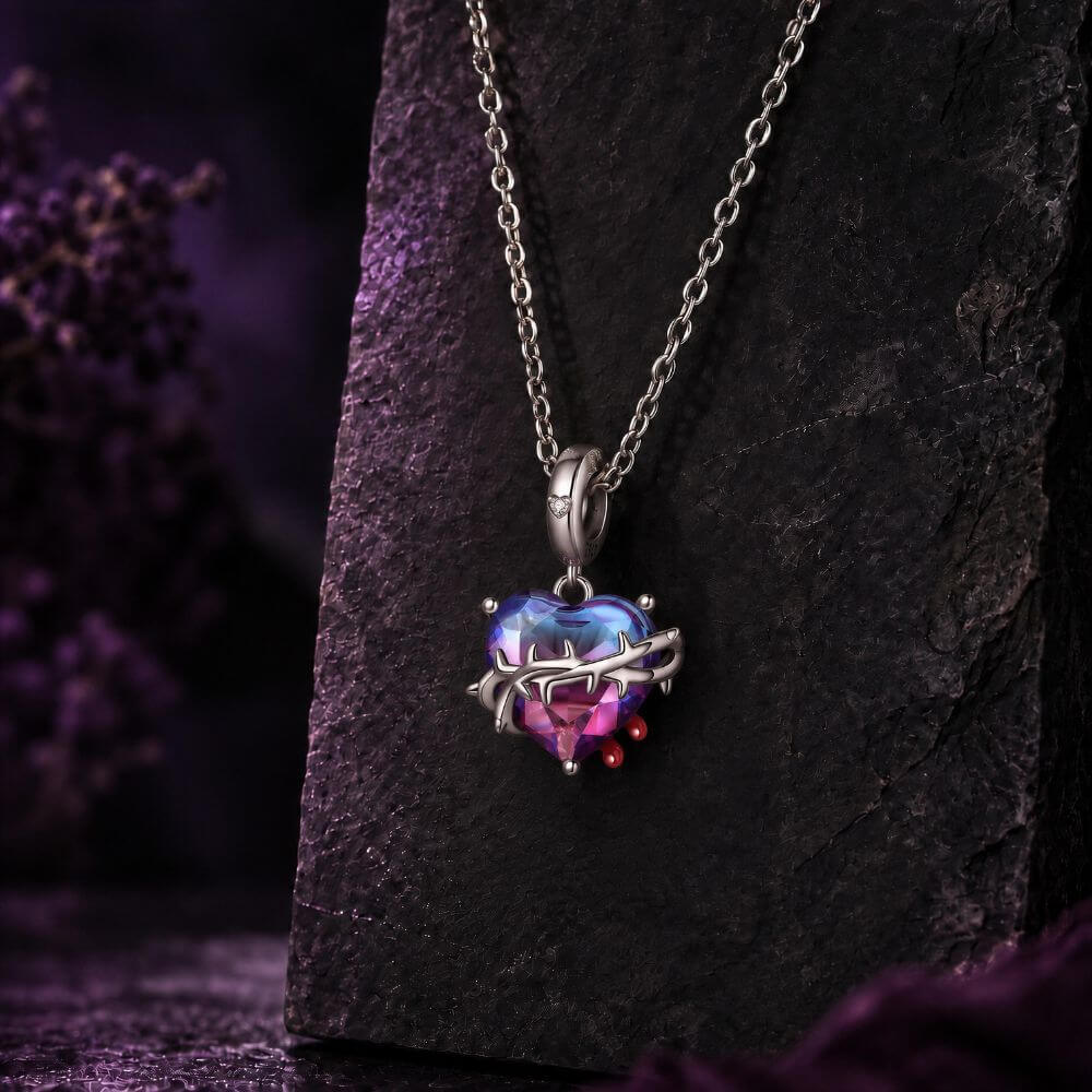 Sterling silver heart charm with blue pink crystal, thorned vine detail, and red drop accents.