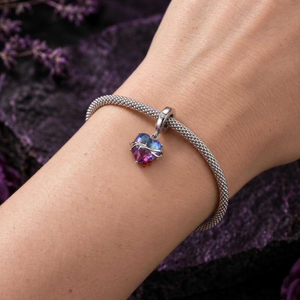 Sterling silver heart charm with blue pink crystal, thorned vine detail, and red drop accents.