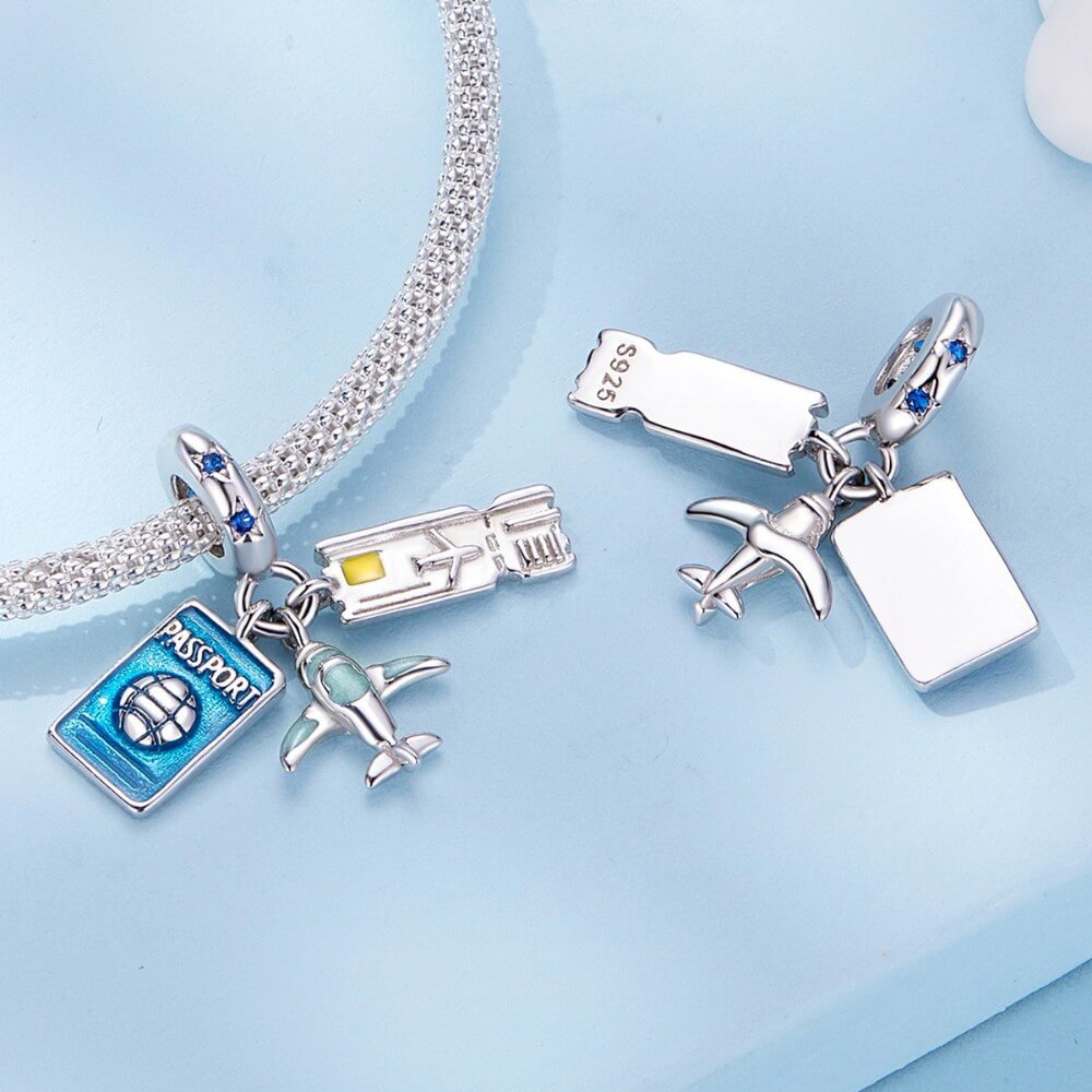 Silver charm bracelet with travel-themed charms on a light blue background