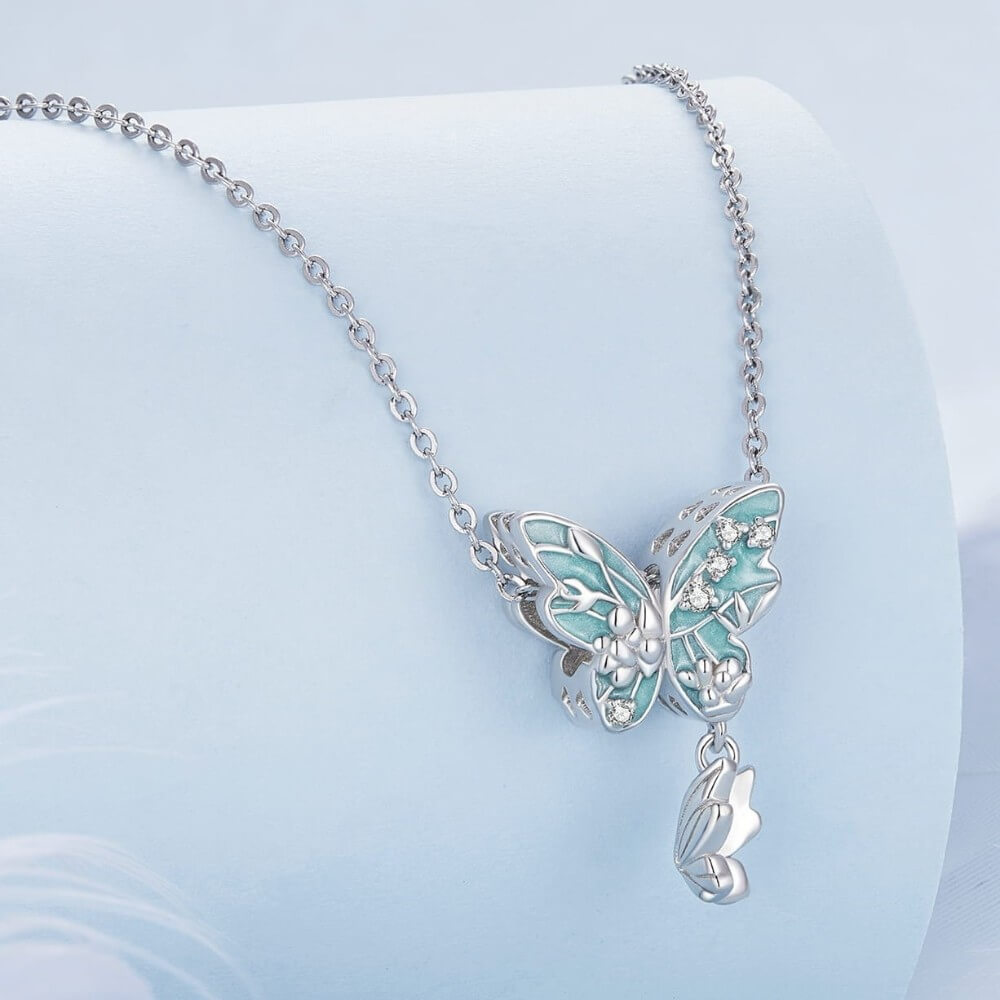 Sterling silver butterfly charm with turquoise enamel, floral details, and crystal accents.
