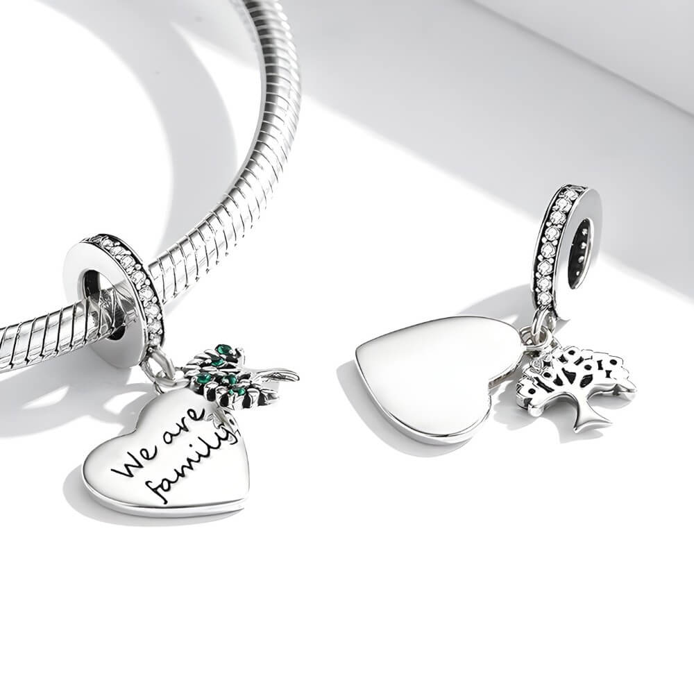 Sterling silver heart charm engraved “We are family” with green gemstones and cross detail.
