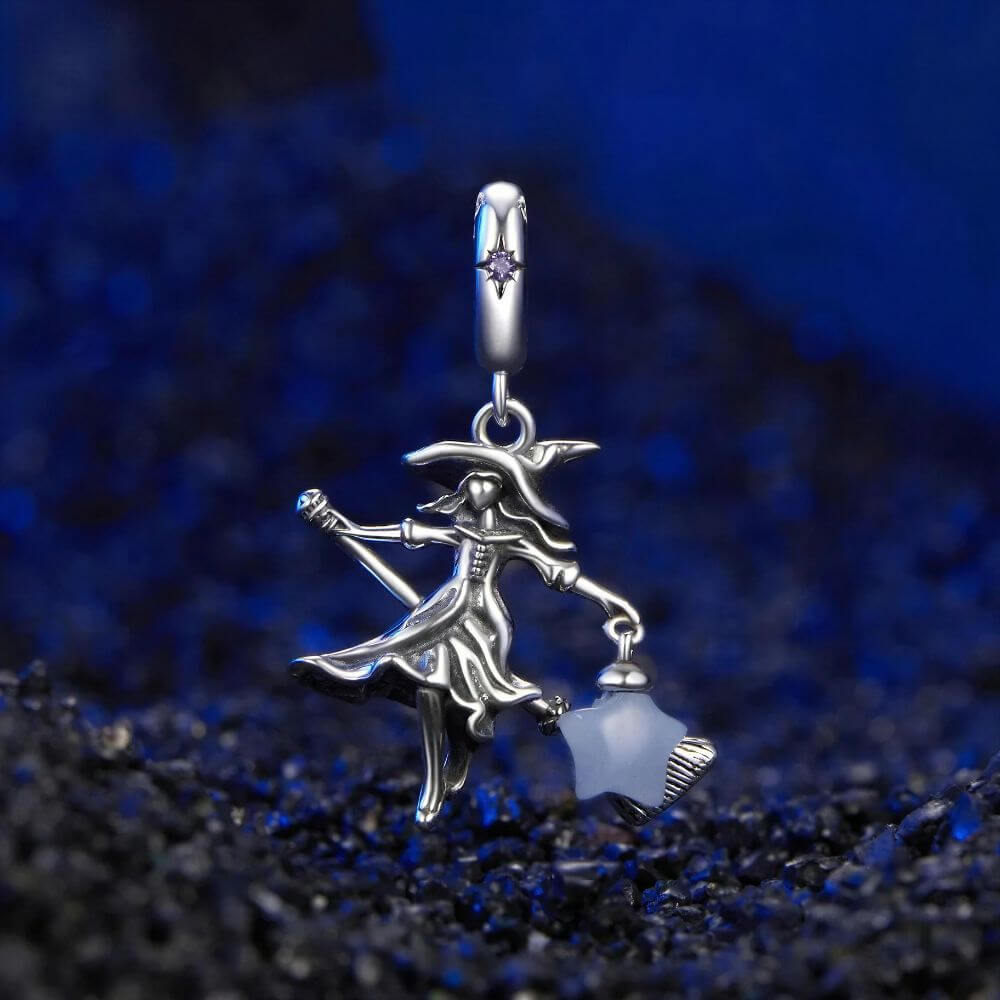 Sterling silver witch charm with broomstick, flowing dress, purple crystal, and glowing blue star lantern.