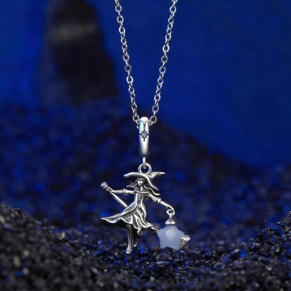 Sterling silver witch charm with broomstick, flowing dress, purple crystal, and glowing blue star lantern.