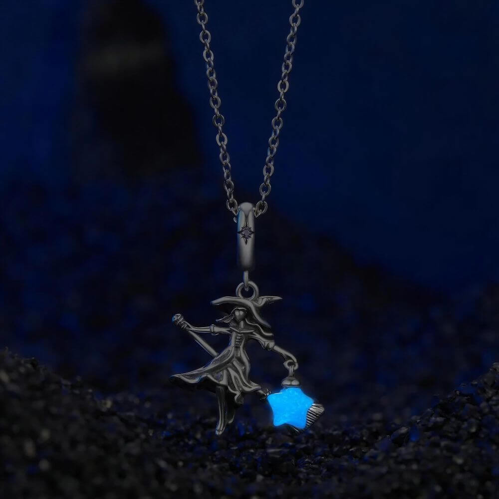Sterling silver witch charm with broomstick, flowing dress, purple crystal, and glowing blue star lantern.